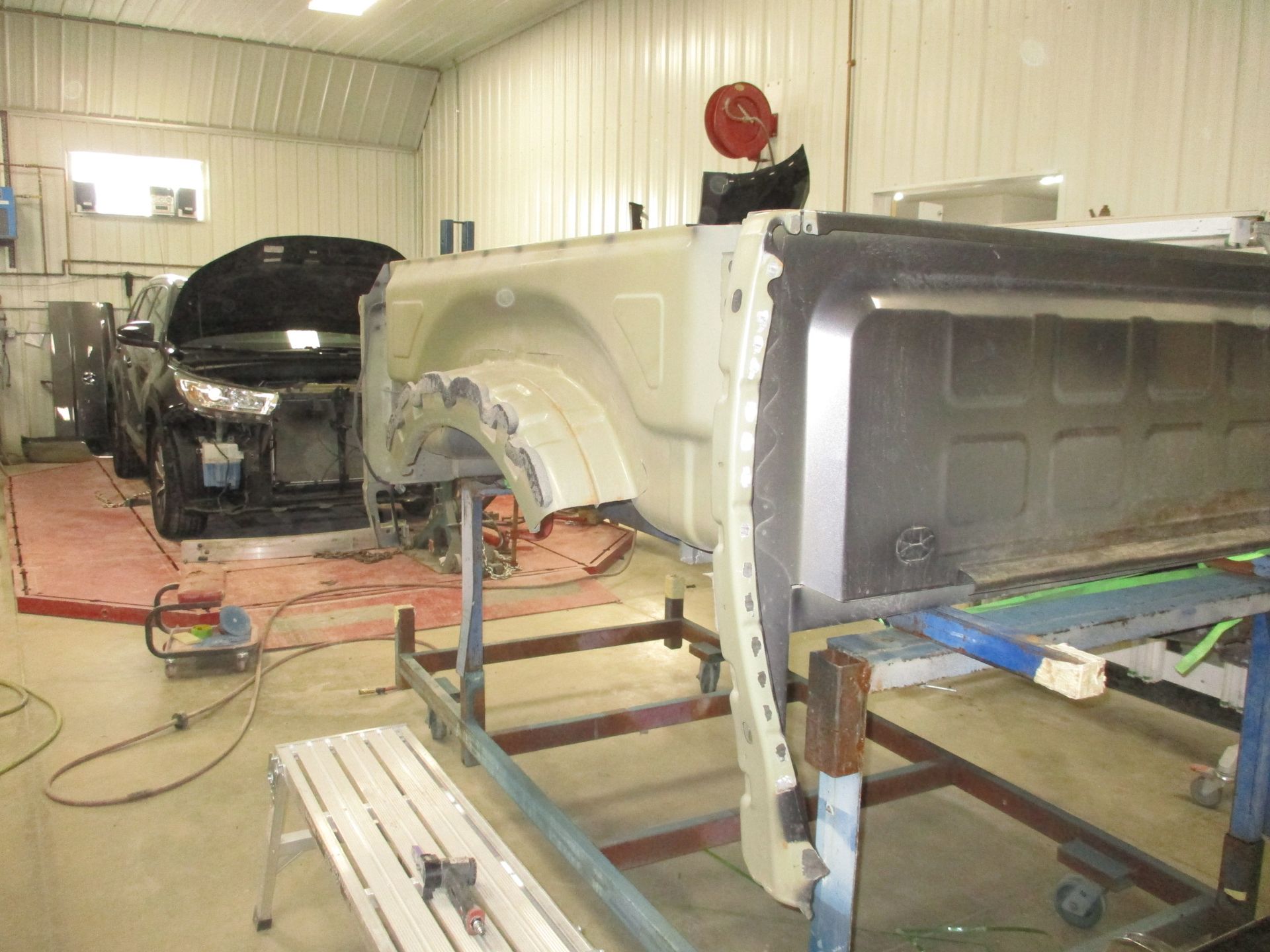 Auto body shop with two car frames under repair, one black and one white, in a workshop.