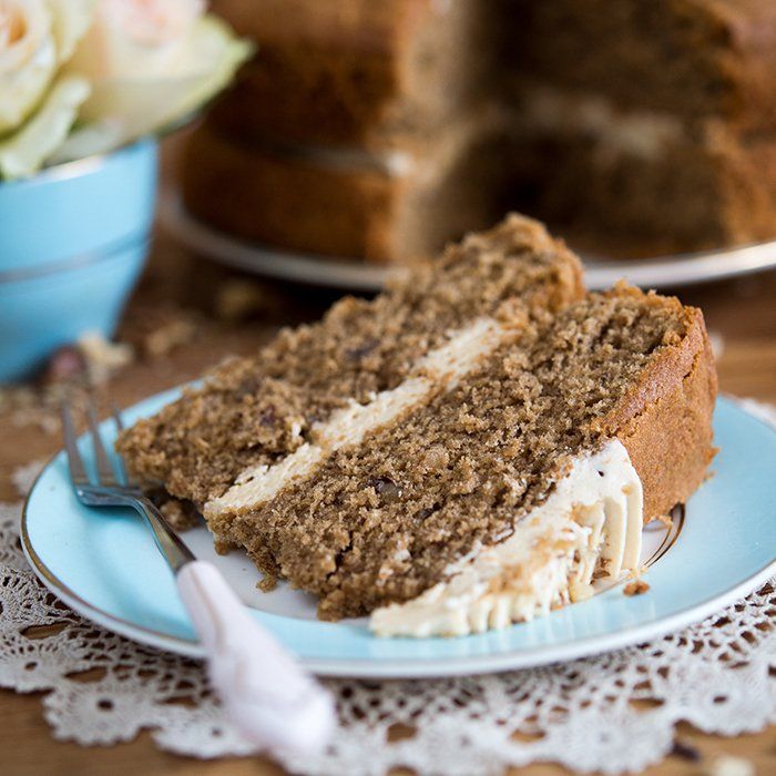 Slice of layered cake with cream filling on a blue plate; a cake in the background.