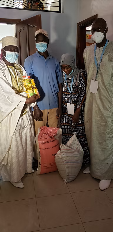 Four masked people standing indoors with sacks and a bag of supplies.