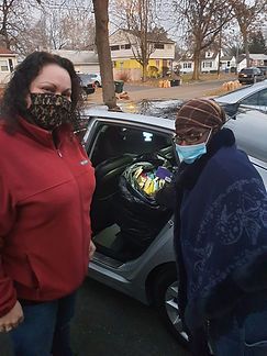 Two masked people stand by an open car door, with bags visible inside the vehicle.