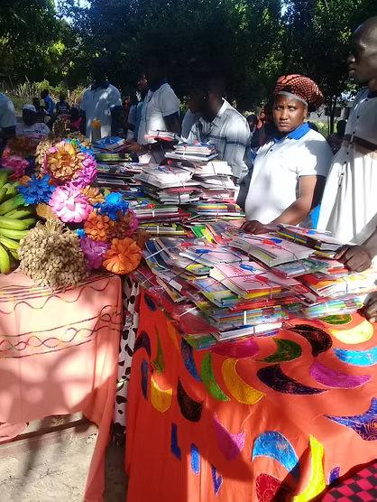 Outdoor market stall with colorful folded clothes and flowers on patterned tablecloths