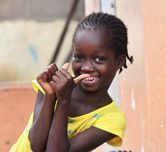 Smiling child in a yellow shirt leaning against a peach-colored wall