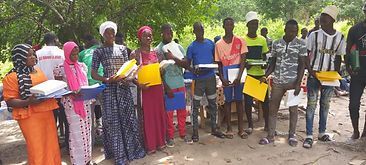 Group of people standing outdoors holding yellow and orange containers, with trees in the background