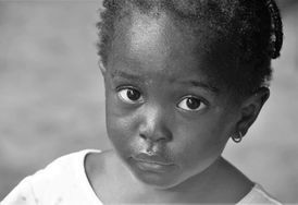 Close-up black-and-white portrait of a child looking at the camera with a neutral expression