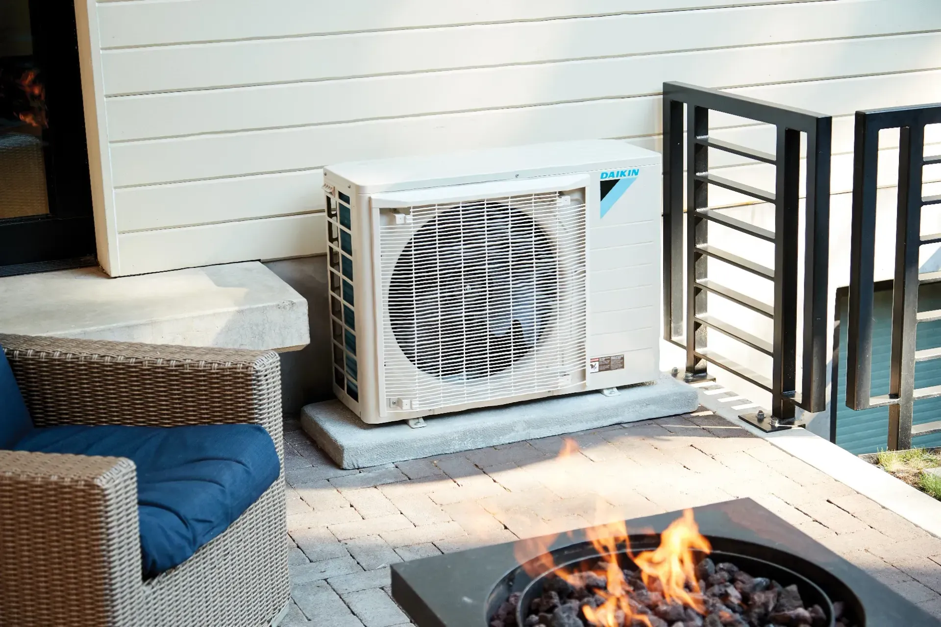 Outdoor air conditioning unit next to a deck, with fire pit in foreground.