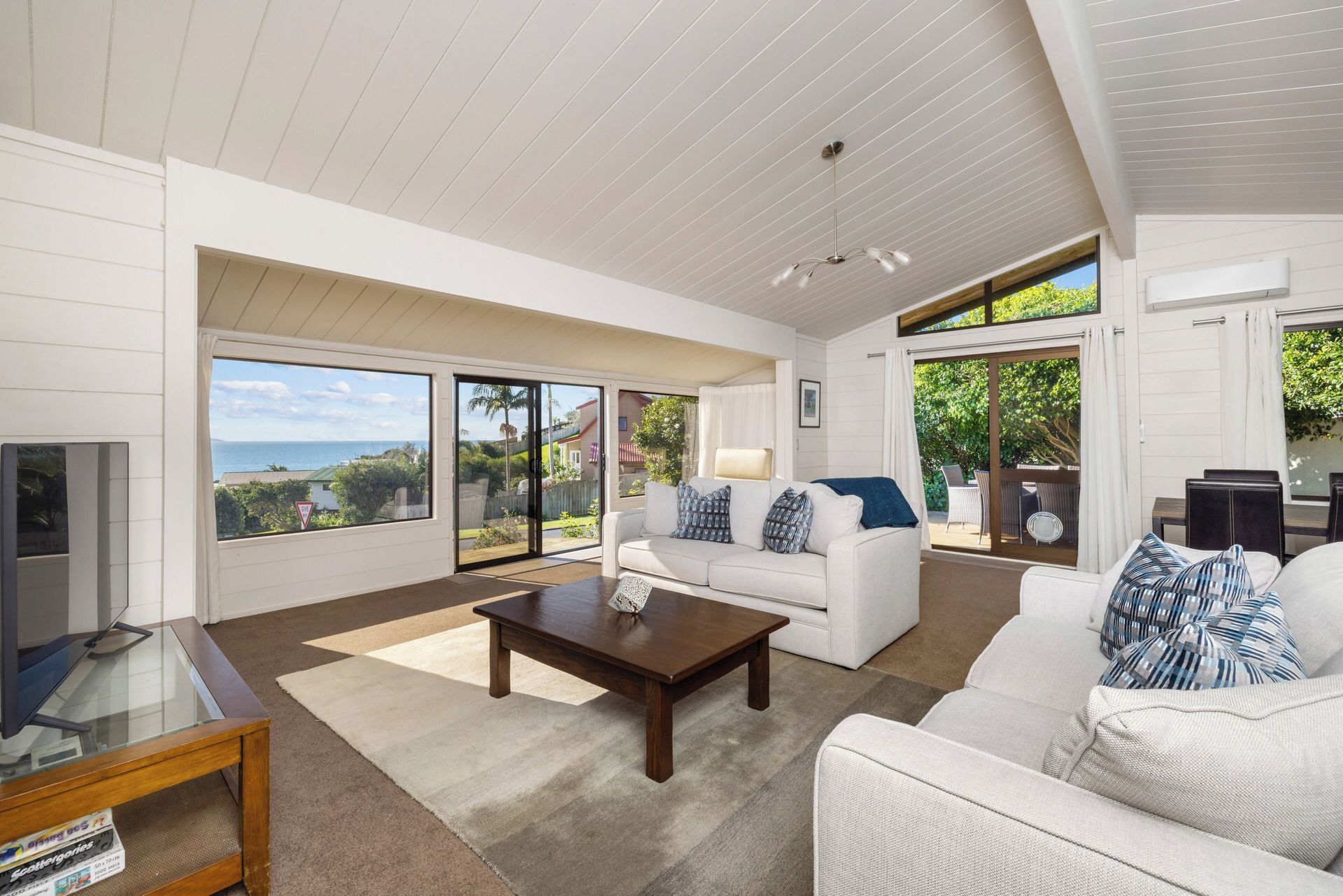 Living room with ocean view, white walls, two couches, coffee table, and large windows.