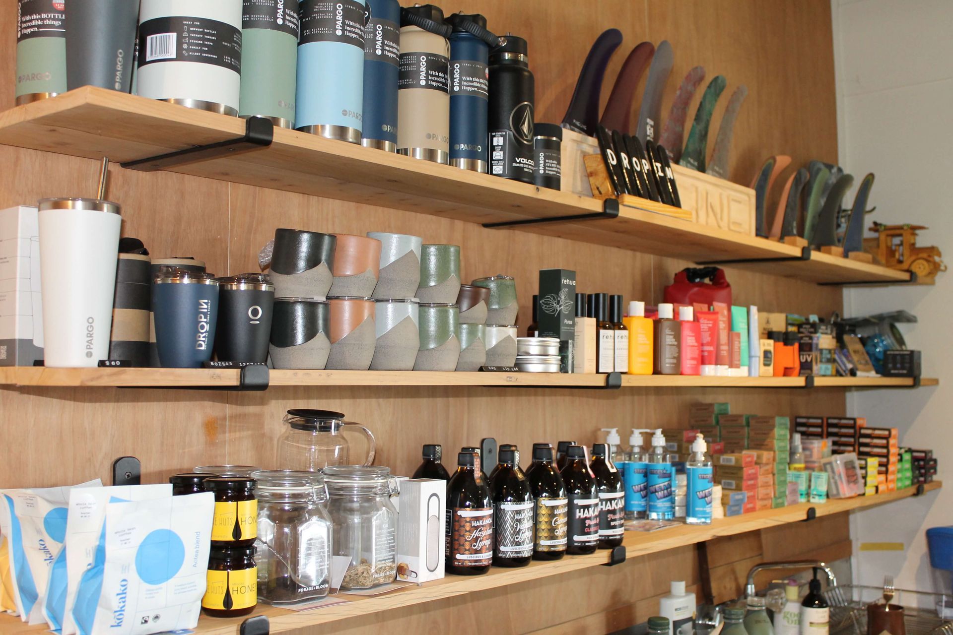 Shelves with assorted merchandise: travel mugs, fins, bottles, and jars, displayed in a store.