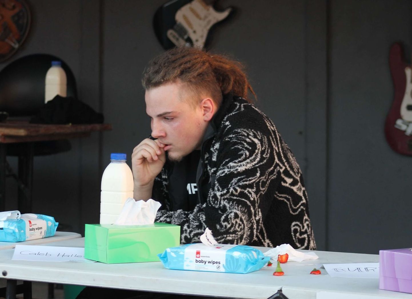 Man at table with milk, tissues, and chilis, looking distressed.