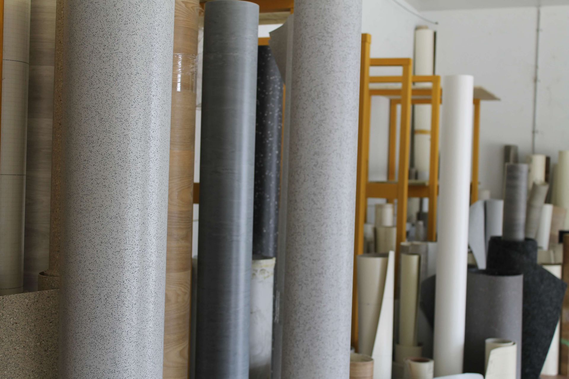 Rolls of various flooring materials in a storage room.