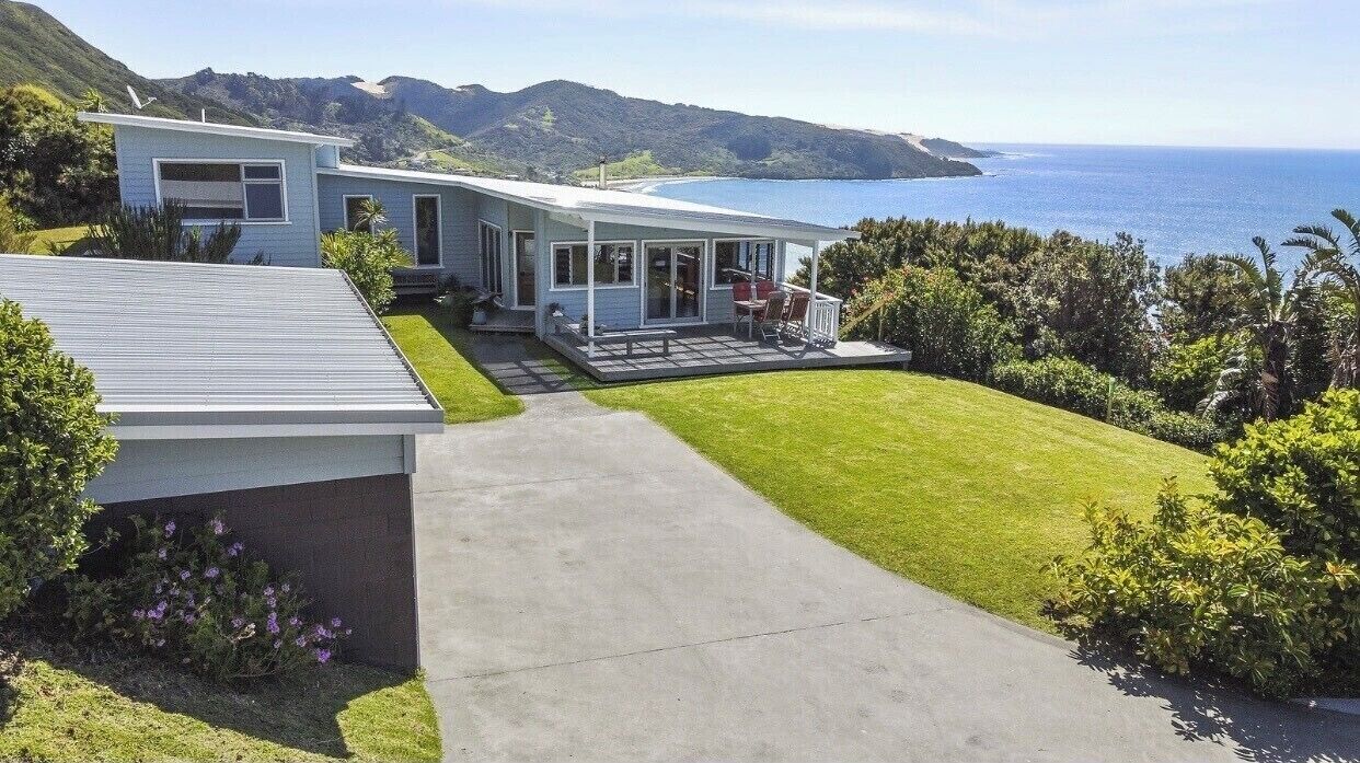 Aerial view of a holiday house with a balcony, surrounded by the sea and greenery