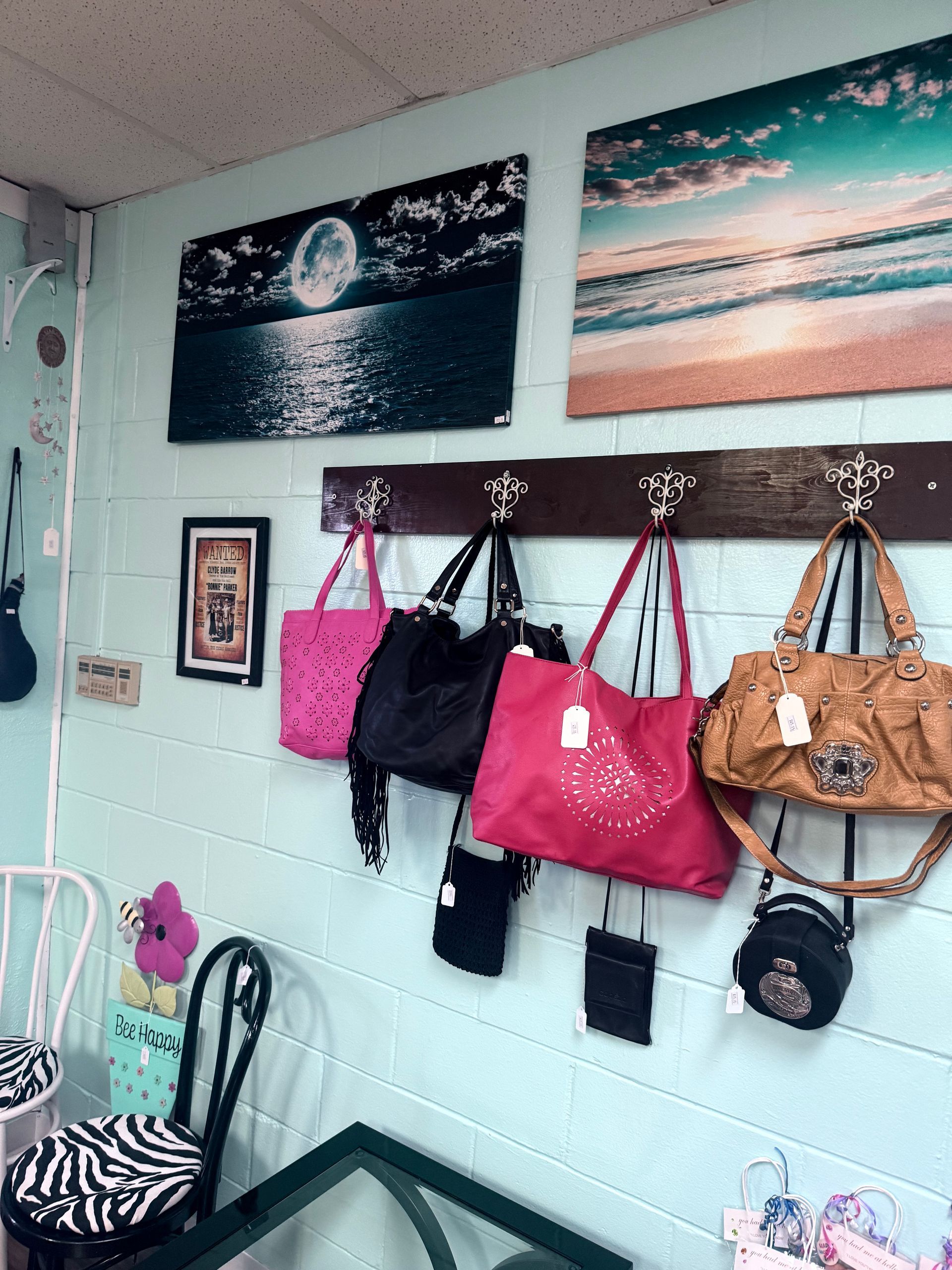 Wall with hanging handbags, framed beach prints, and a zebra-print chair in a pastel room