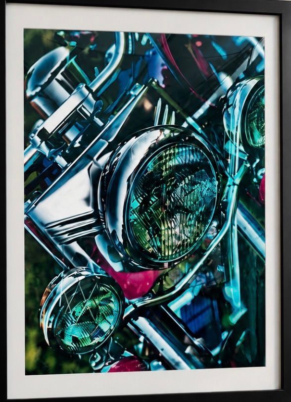 Abstract close-up of chrome motorcycle headlights with teal, blue, and pink reflections