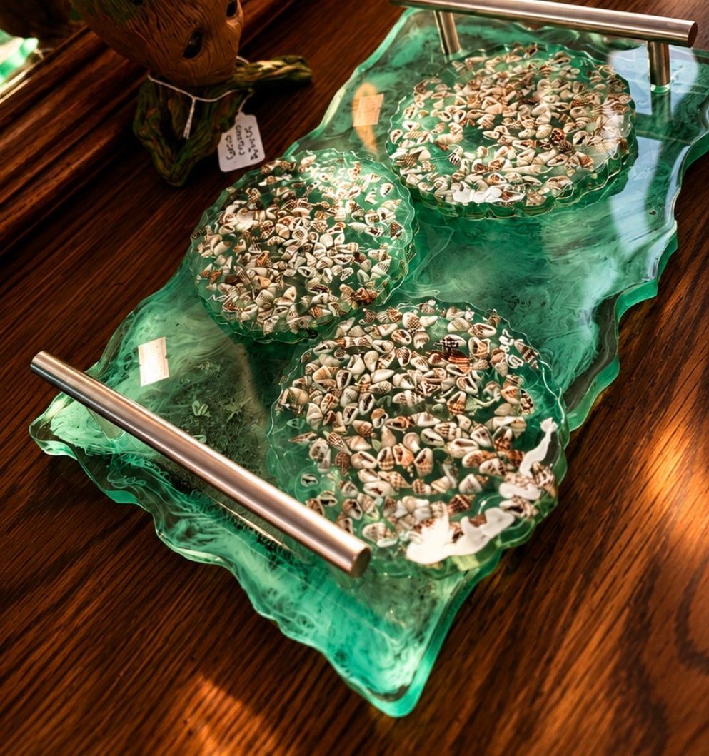 Green glass tray with three round coconut-topped treats on a wooden table