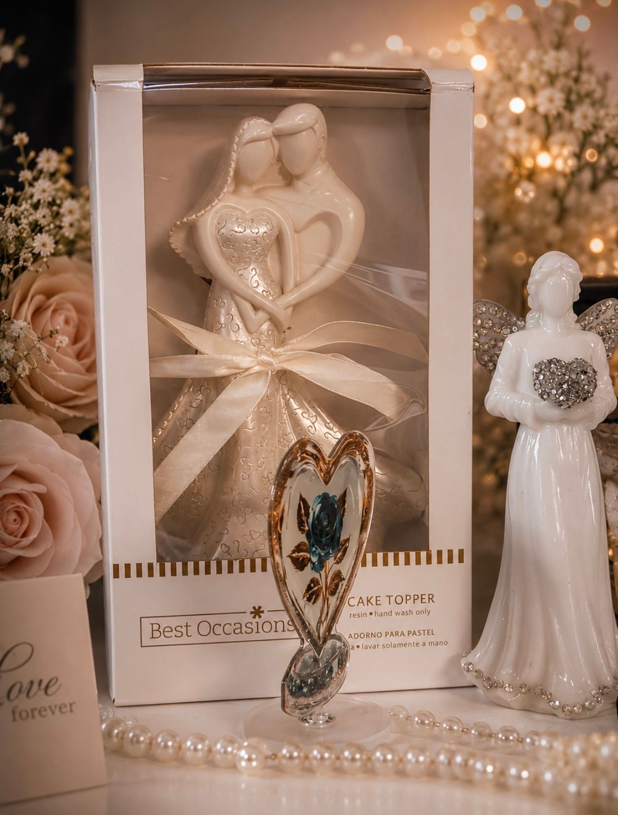 Decorative wedding-themed gift box with white heart ornament, pearl necklace, and figurine on a soft-lit table