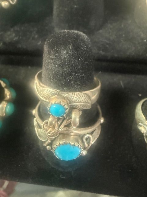 Silver ring with turquoise stones displayed on a black velvet stand