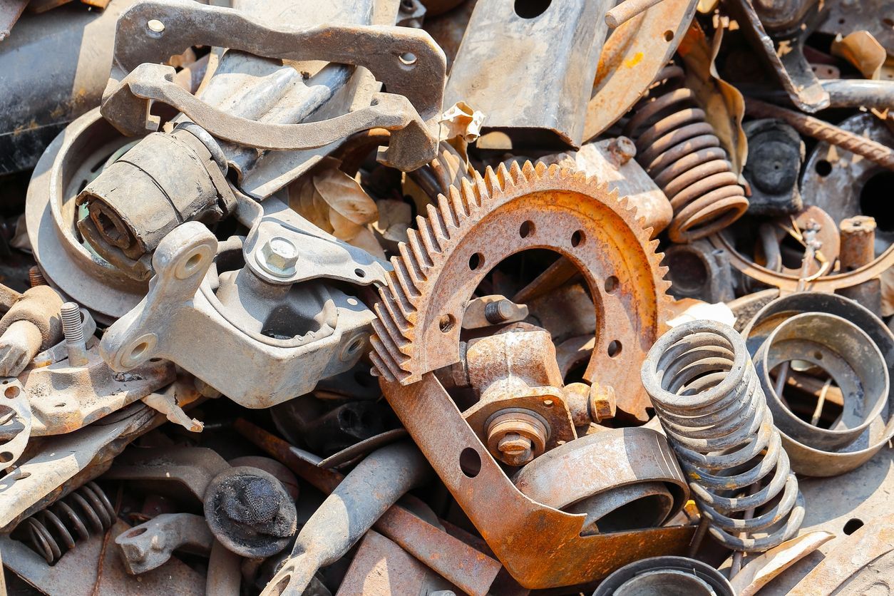 Pile of rusty metal car parts, including gears, springs, and brackets.