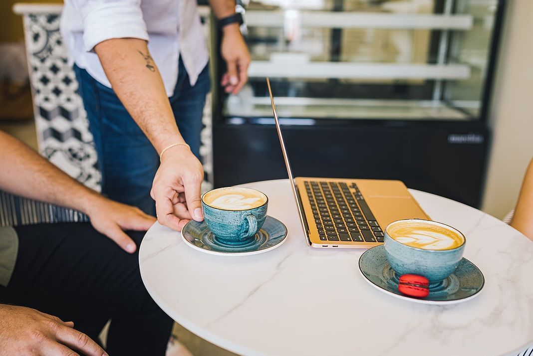 A cup of cappuccino is sitting on a saucer on a table.