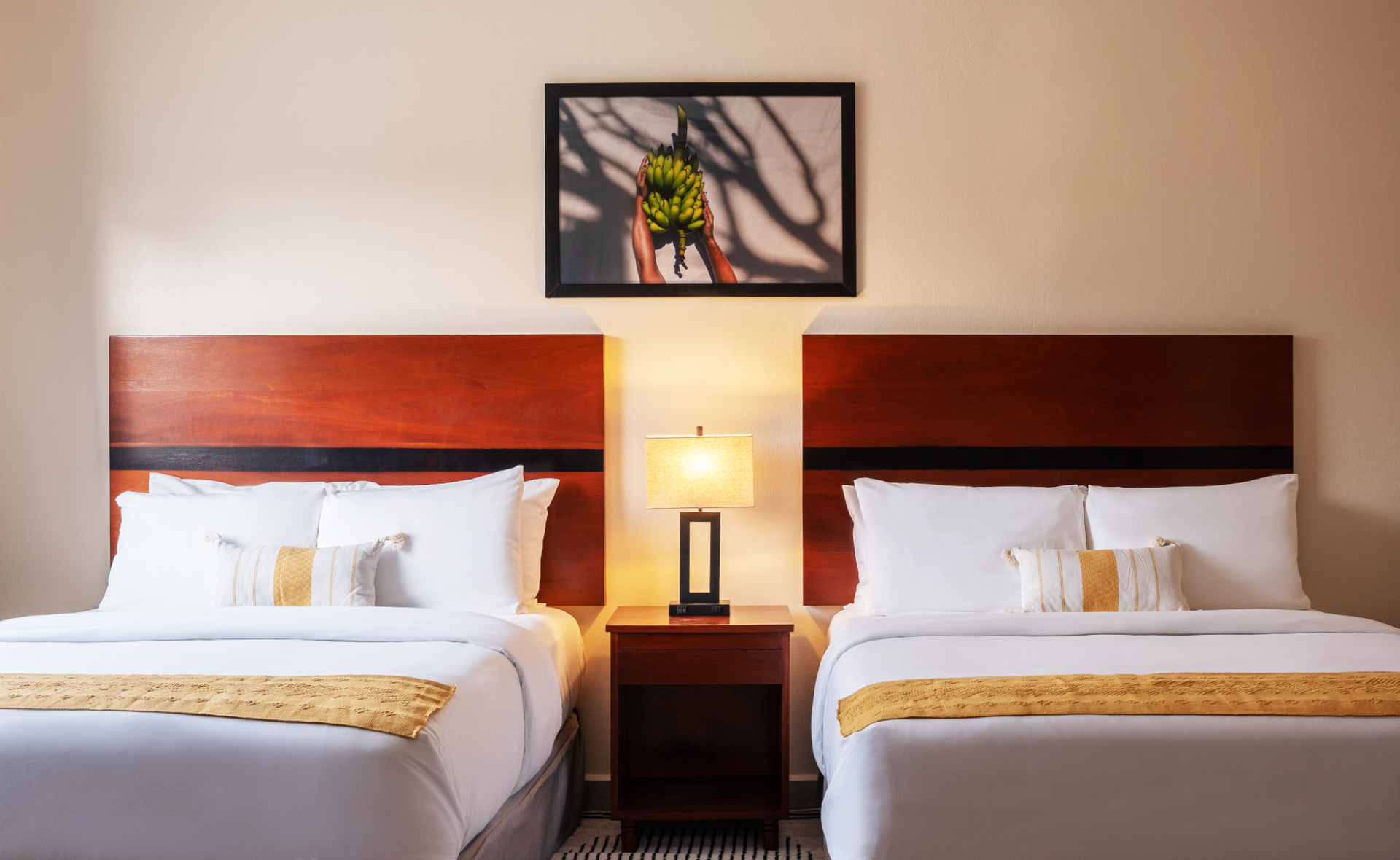 A hotel room with two beds , a nightstand , a lamp and a picture on the wall.