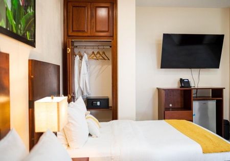 A hotel room with a bed and a flat screen tv