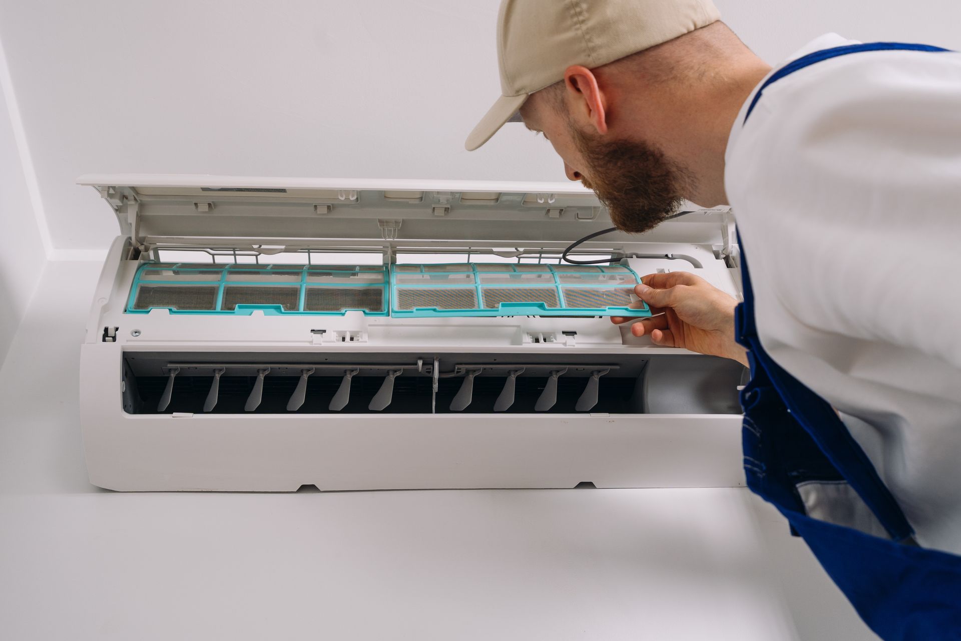 Technician repairing wall-mounted AC unit for reliable cooling performance. Technician repairing wall-mounted AC unit for reliable cooling performance.