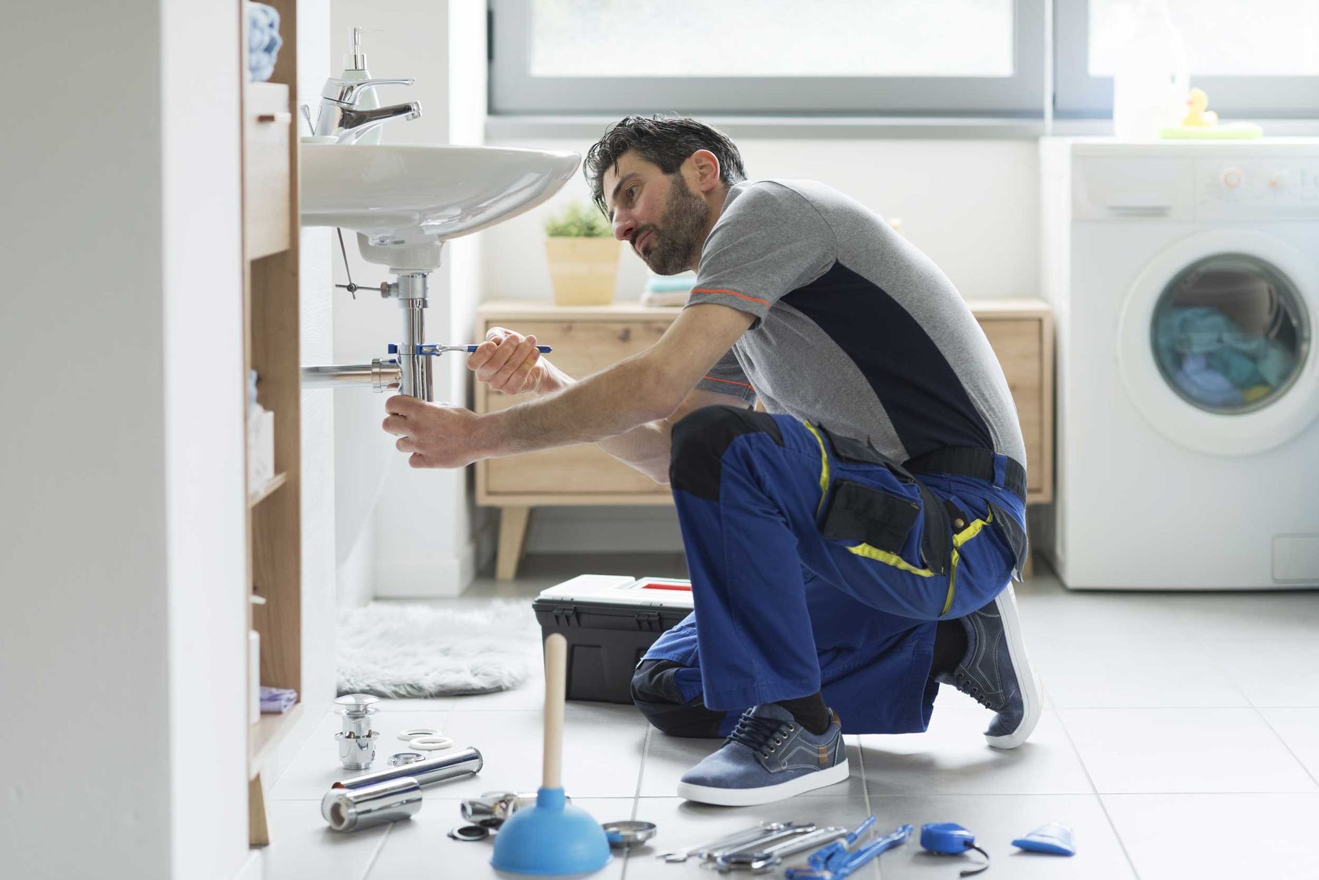 Plumbing installation contractor working on a bathroom sink in a home. Plumbing installation contractor working on a bathroom sink in a home.