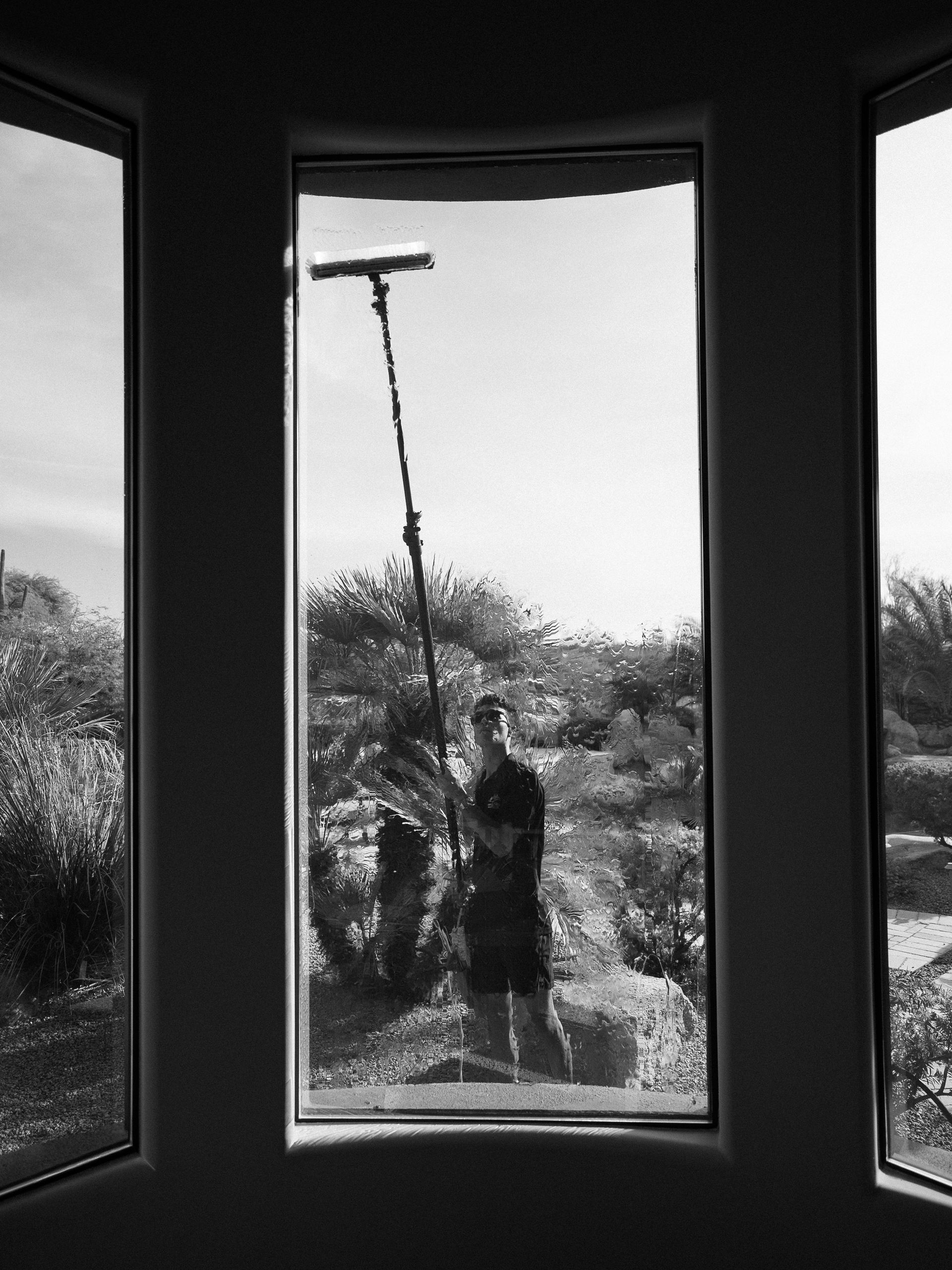 Person using a long-handled tool outdoors, viewed through a window