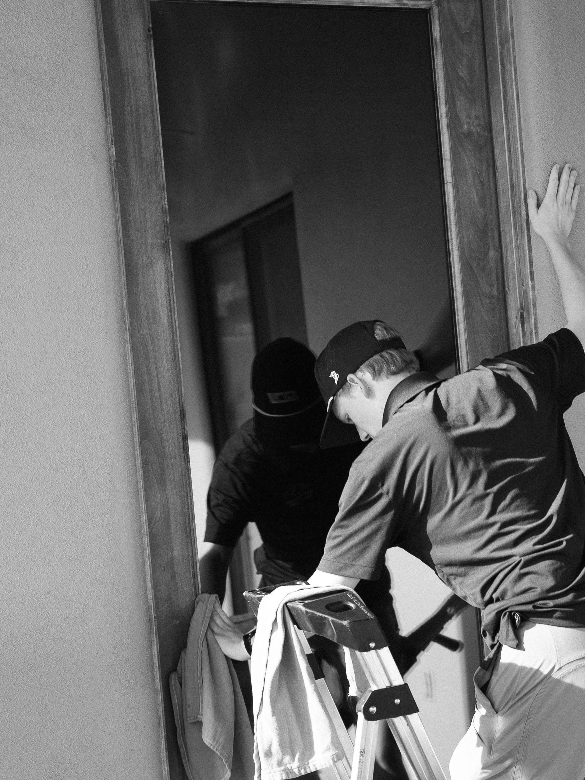 Two workers carrying a washing machine through a doorway in a narrow hallway