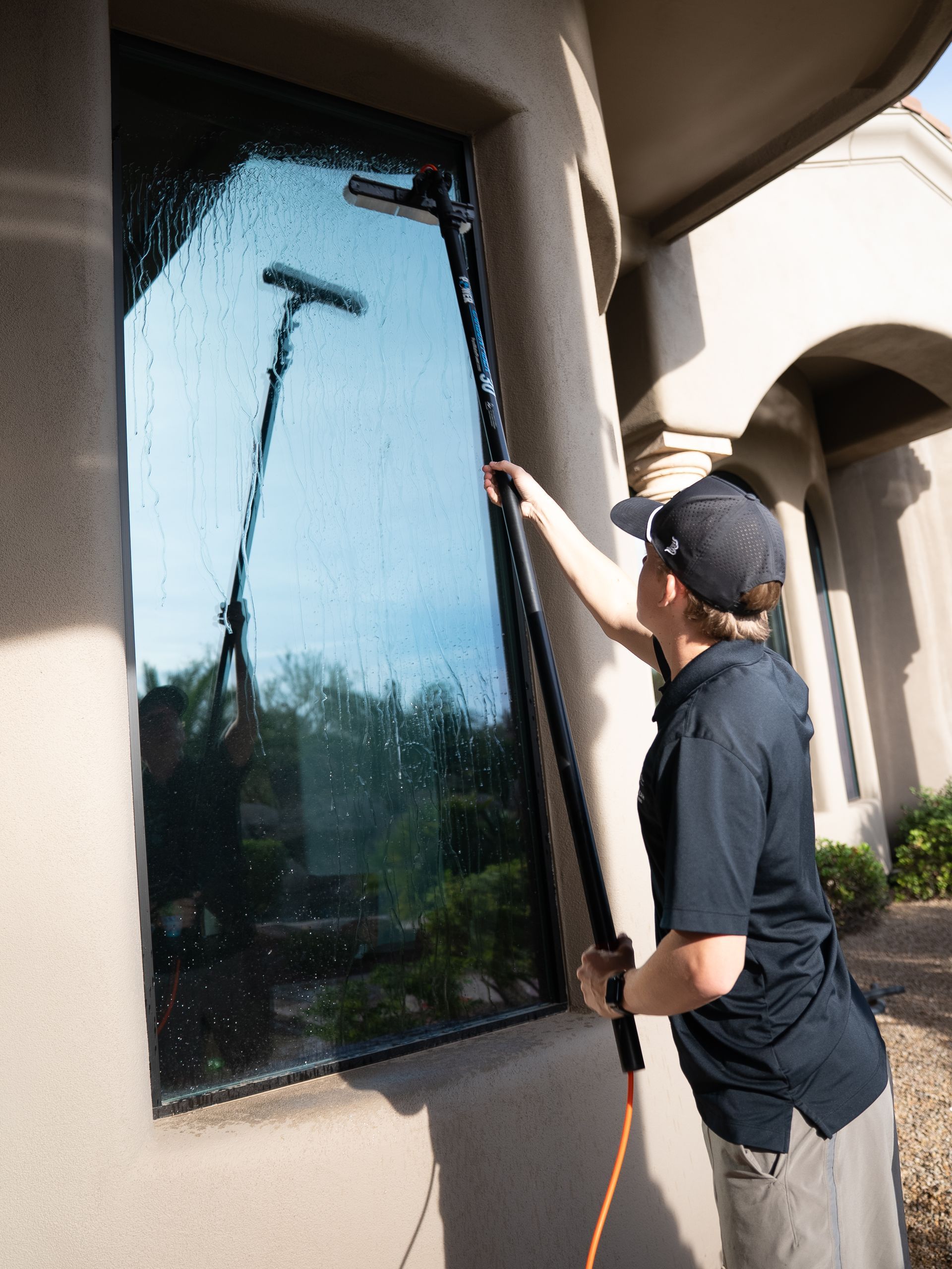 Person cleaning a large window with a squeegee on a building exterior