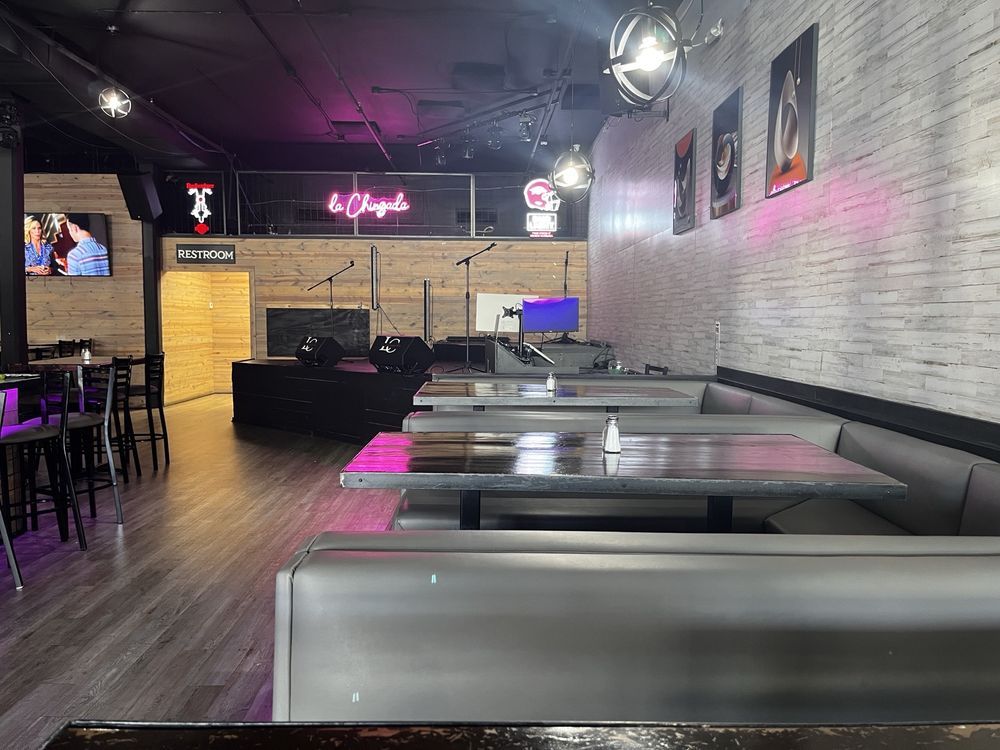 Empty retro diner interior with gray booths, wood floor, and pink neon lighting