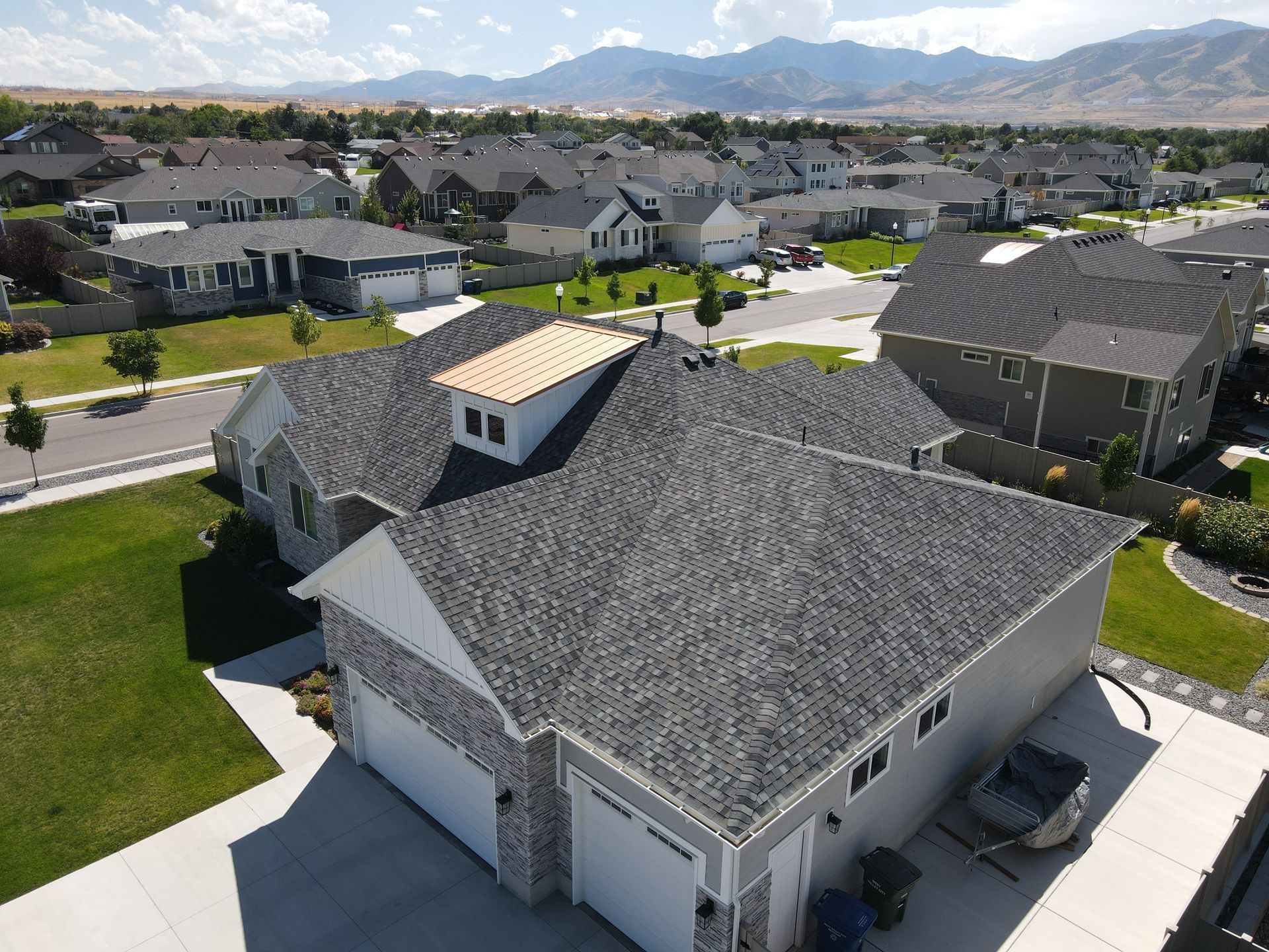 An aerial view of a house in a residential area with mountains in the background