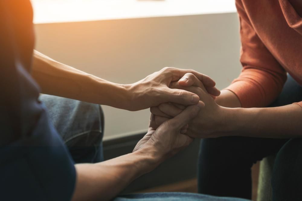 A Man And A Woman Are Holding Hands — Lake Macquarie Counselling & Psychotherapy In Maitland, NSW