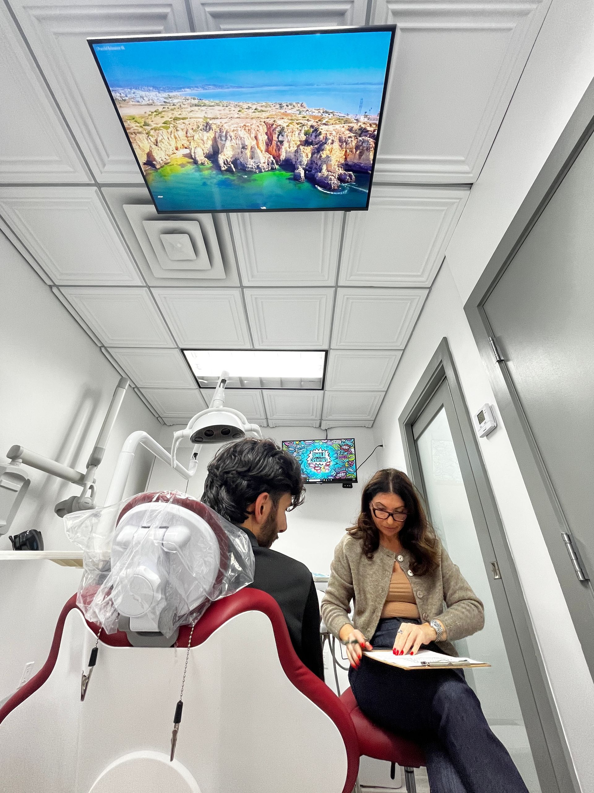 Two surgeons in green scrubs operating on a patient in a dental office.