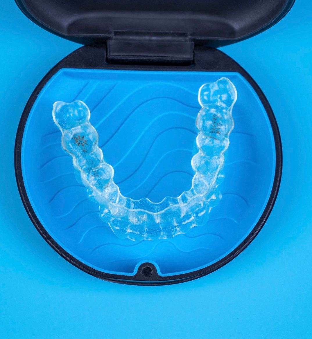 A clear brace is in a blue case on a blue surface.
