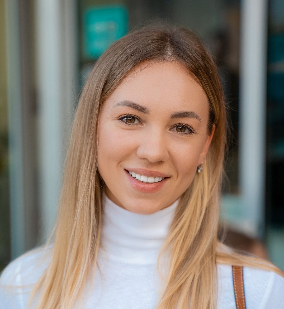 A close up of a woman wearing a white turtleneck and smiling.