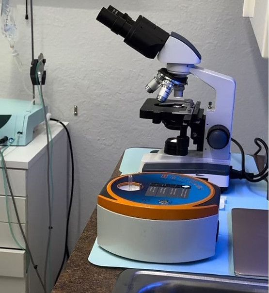 A microscope is sitting on a table next to a sink