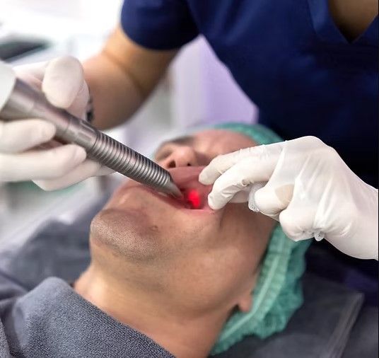 A man is getting a laser treatment on his teeth