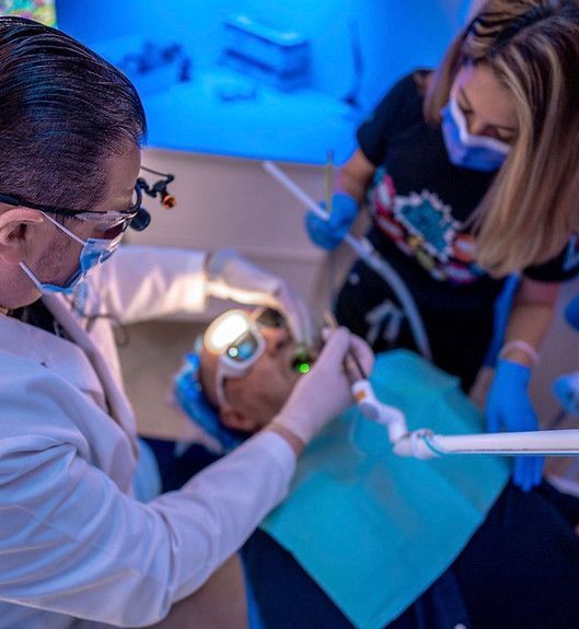 A dentist is examining a patient 's teeth in a dental office.