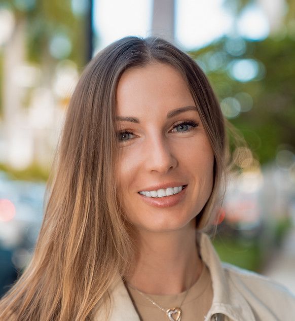 A woman with long hair and a necklace is smiling for the camera.