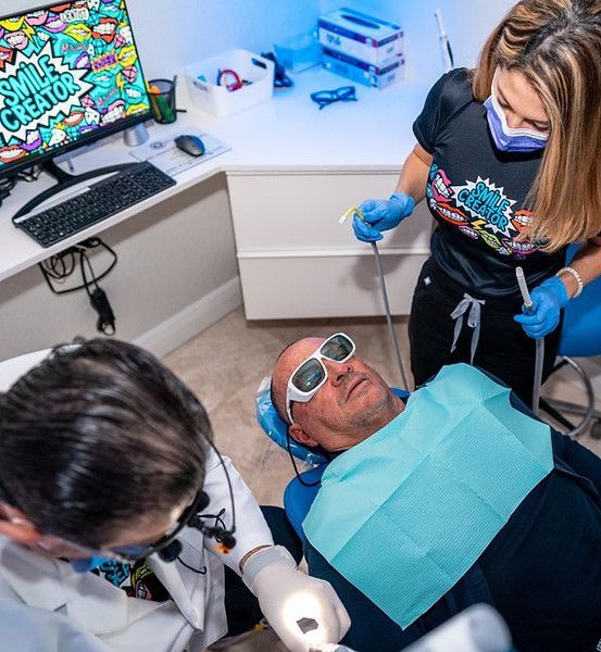 A man is getting his teeth examined by two dentists in a dental office