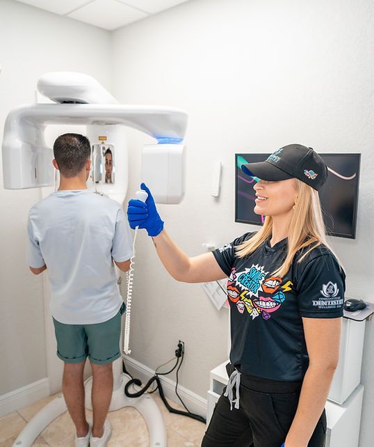 A woman is giving a thumbs up while a man is getting an x-ray of his teeth.