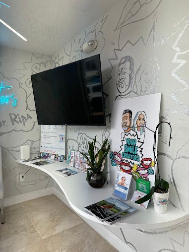 A waiting room with a table and a flat screen tv on the wall.