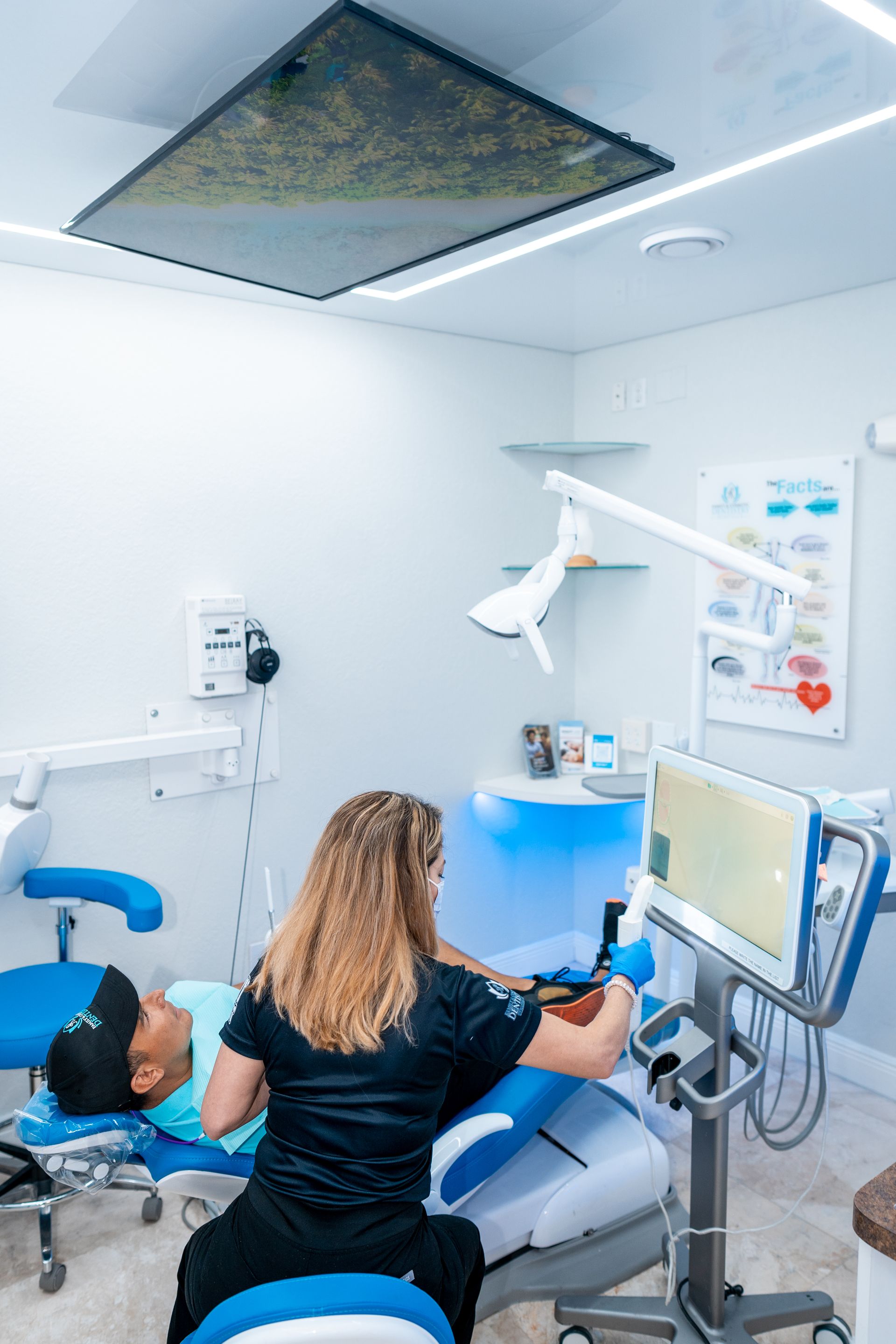 A woman is working on a man 's teeth in a dental office.