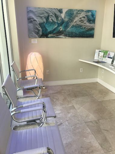 A waiting room with purple chairs and a painting on the wall.