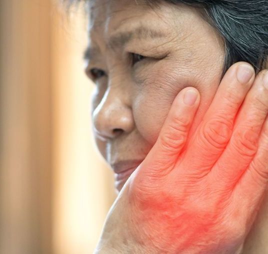 A woman is holding her hand to her face because she has a toothache.