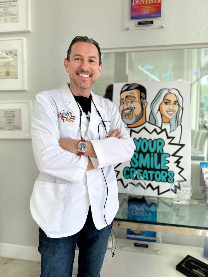 A man in a lab coat stands in front of a sign that says your smile creators