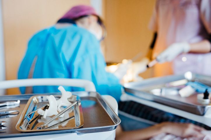 Medical personnel performing surgery, surgical tools tray in the foreground.