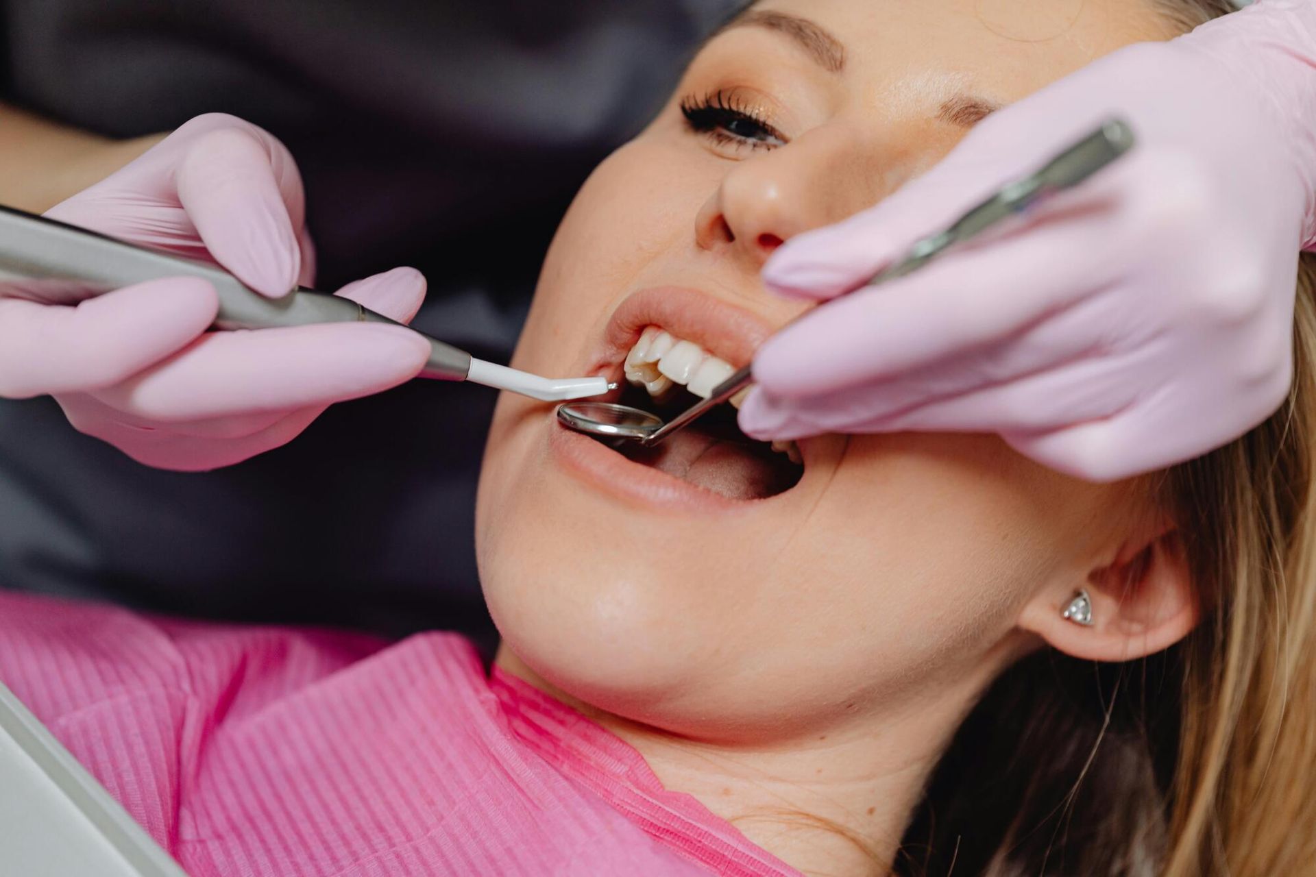 Dentist examining a patient’s teeth with a mirror and tools, close-up in a dental chair