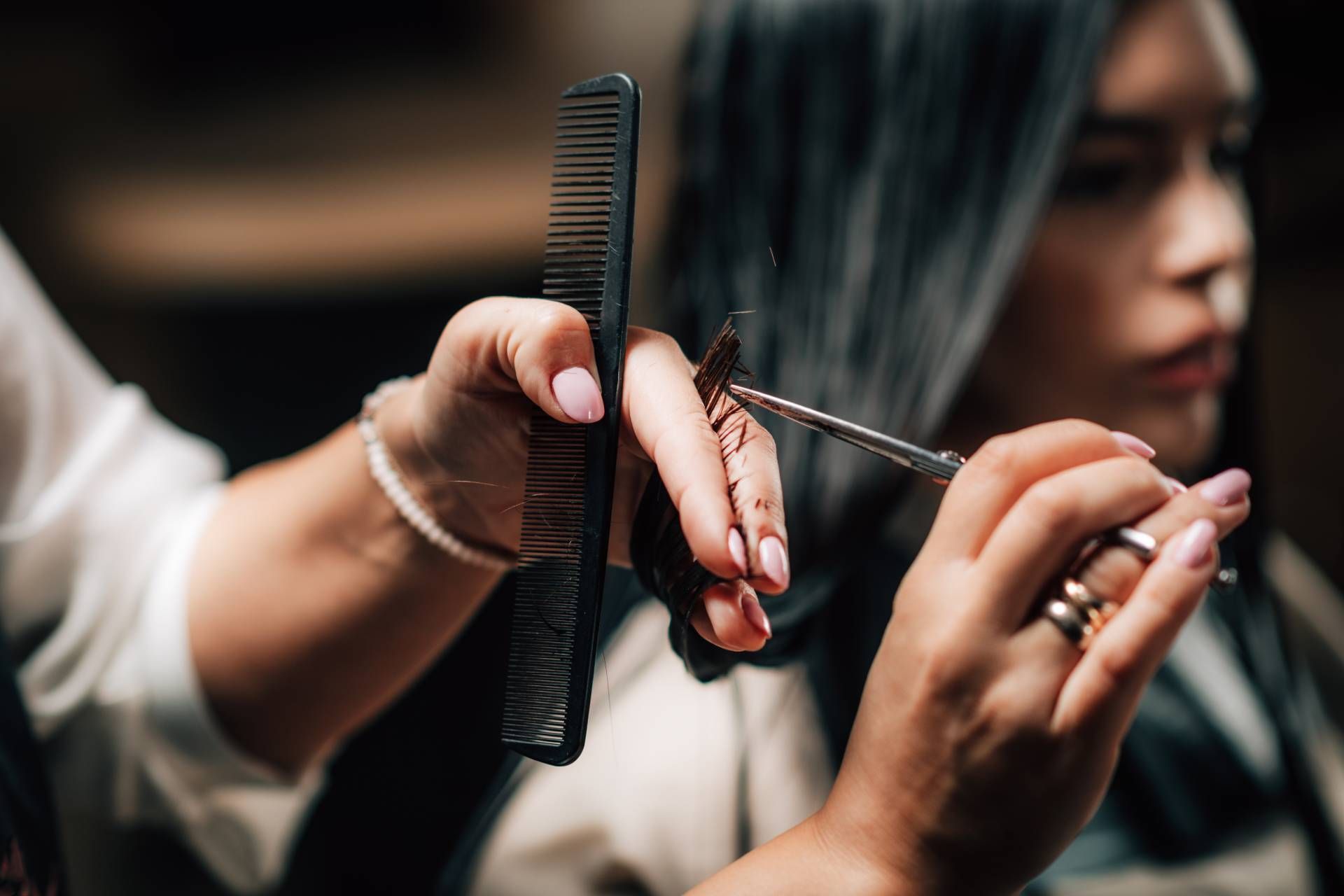 Hair stylist trimming long hair with scissors and a comb