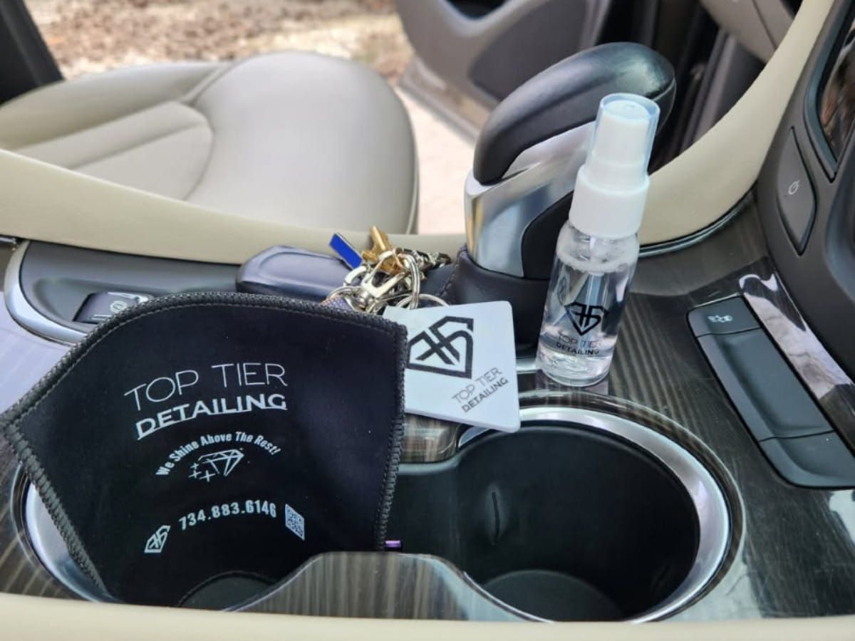 Top Tier Detailing microfiber towel and car care products inside a vehicle center console.