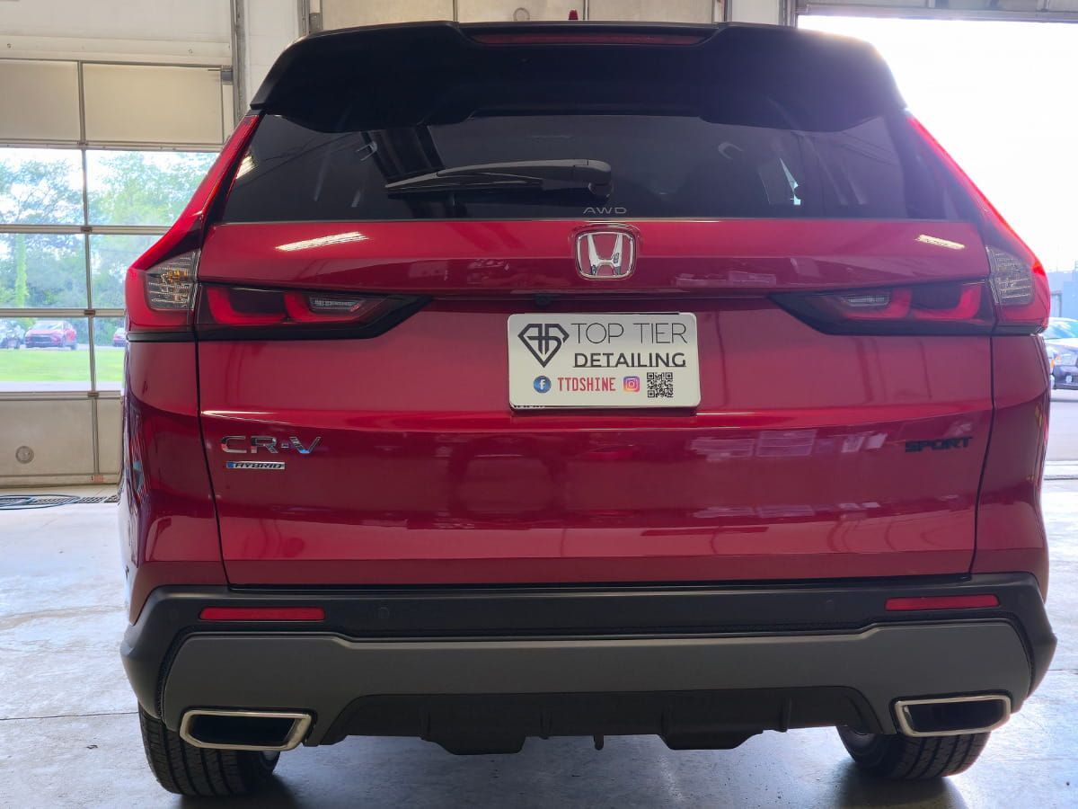 Rear view of a red Honda CR-V Hybrid with a glossy finish inside the detailing shop.